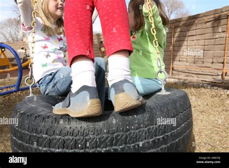 Girls Swinging On A Tire Swing Outdoors Stock Photo Alamy