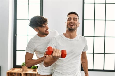 Two Hispanic Men Couple Smiling Confident Training Using Dumbbell At
