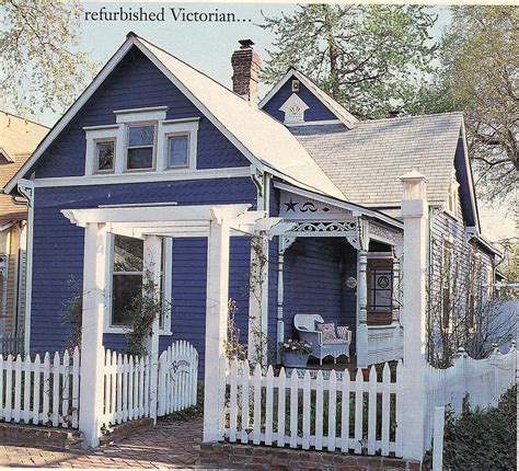 A Blue House With White Picket Fence In Front Of It And The Words