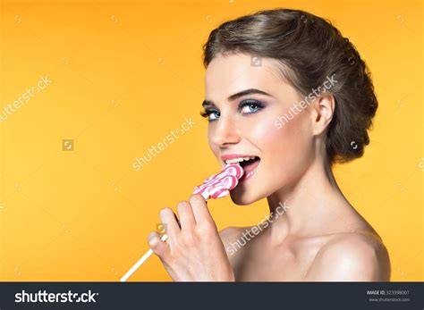 Beautiful Young Woman With Pink Candy Over Yellow Backgroung Розовый