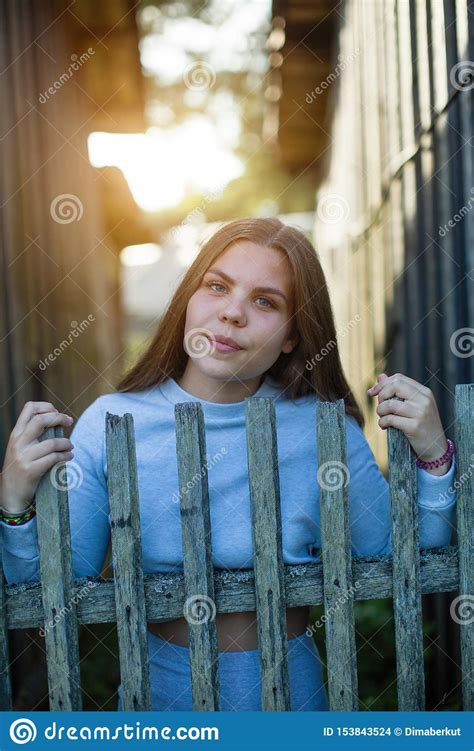 Young Teenage Girl Posing Near The Fence In The Village Stock Photo