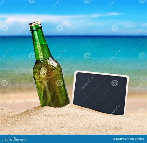 Пивная бутылка в песке на пляже и классн классном Стоковое Фото изображение насчитывающей