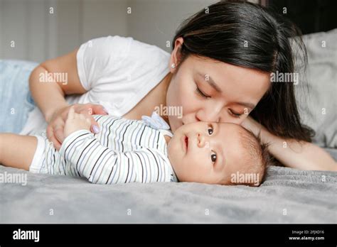 día de las madres orgullosa madre asiática abrazando besando hijo recién nacido fotografía de