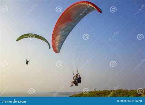 Two Tandem Paragliders On White Red And Green Parachutes Fly Over The