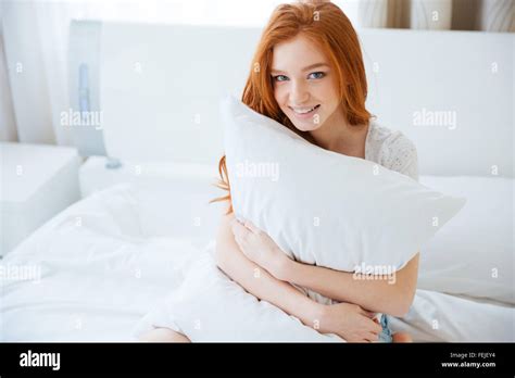 Happy Redhead Woman Holding Pillow On The Bed At Home Stock Photo Alamy