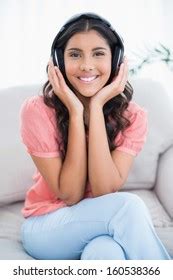 Cheerful Cute Brunette Sitting On Couch Stock Photo