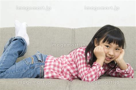 ソファに寝転ぶ女の子の写真素材 24010117 イメージマート