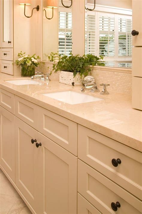 A Bathroom With Double Sinks And White Cabinets
