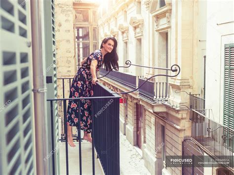 Woman Standing On Balcony In City Buildings Tiptoe Stock Photo