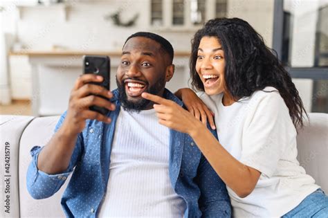 no way surprised multiracial couple looks at the smartphone screen with astonishment african