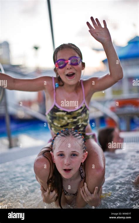 Portrait Of Two Girls Giving Each Other A Shoulder Ride While Having Fun In A Swimming Pool