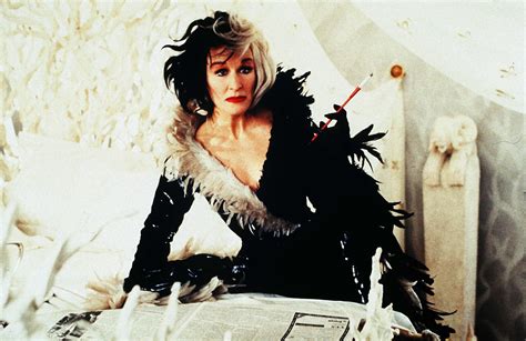 A Woman Sitting On Top Of A Bed Wearing Black And White Clothes With Feathers Around Her Body