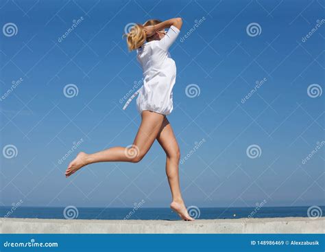 Barefoot Girl In White Short Dress Running Along Breakwater Stock Image