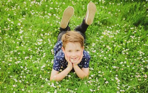 Happy Kid Lying On Flower Lawn Cute Child Boy Enjoying On Field Stock