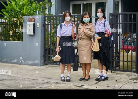 A Thai Teacher And Her Daughters All Dressed In Their School Uniforms