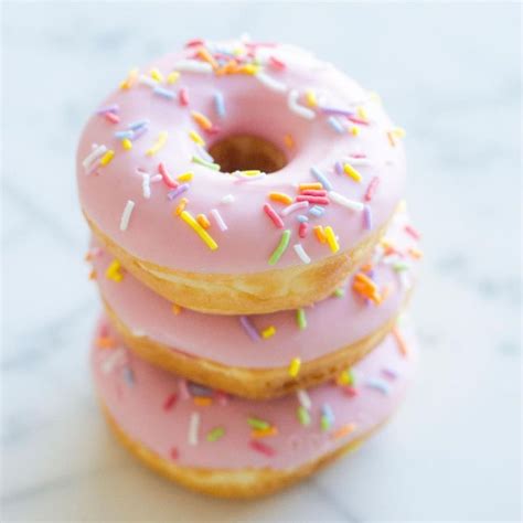 Three Donuts With Pink Frosting And Sprinkles Stacked On Top Of Each Other