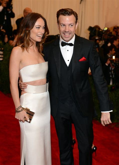 A Man In A Tuxedo Standing Next To A Woman In A White Dress