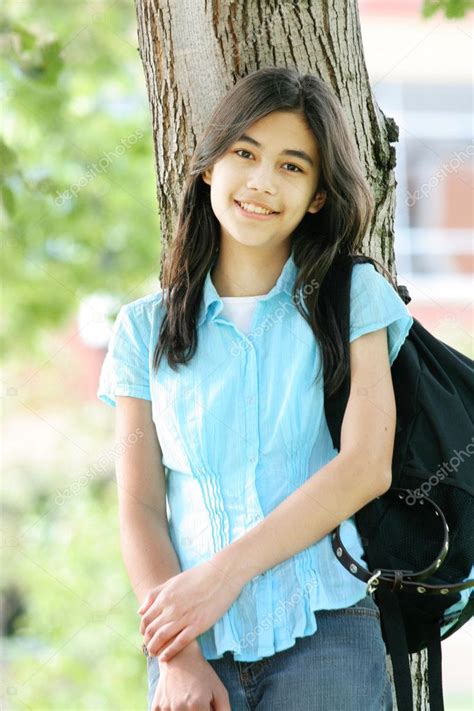 Young Teen Girl Standing With Backpack By Tree Smiling