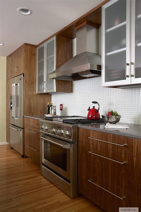 Avoid bold colors that can clash with wood cabinets. Walnut cabinetry with quartz countertop, GE range. Frosted ...