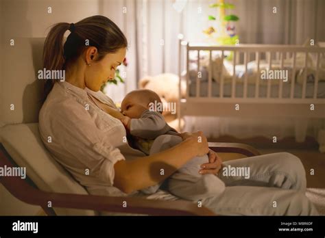 Young Beautiful Mother Breastfeeding Her Newborn Baby Boy At Night