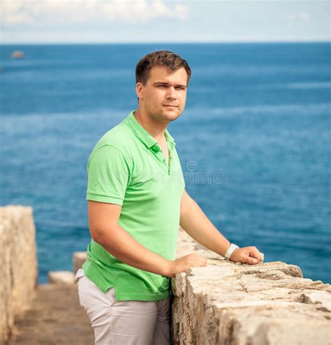 Young Man Standing On Stone Wall At Seaside Fortress Stock Photo
