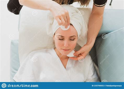 Beautician Makes Facial And Massage To A Young Woman With A Towel On