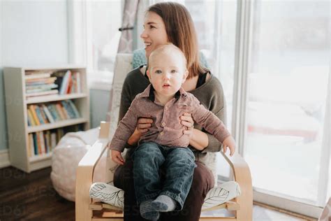 Baby Boy Sitting On Mothers Lap In Living Room Portrait Stock Photo
