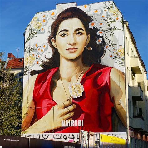 A Large Mural On The Side Of A Building With A Woman Holding A Flower In Her Hand