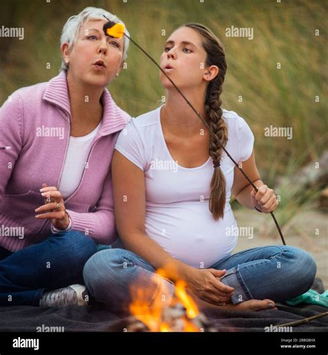 Mature Woman And Her Pregnant Babe Blow On A Burning Marshmallow