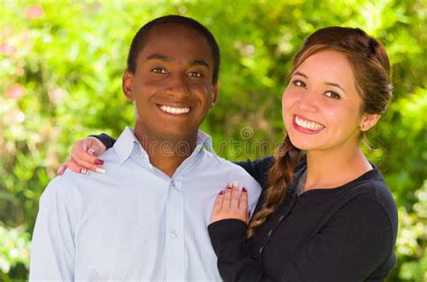 Beautiful Young Interracial Couple In Garden Environment Embracing And