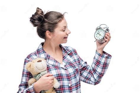 Girl In Pajamas Looks At Alarm Clock And Holds In Hand A Teddy Stock