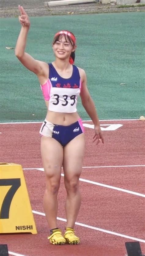 a woman standing on top of a track with her arms in the air and one hand up