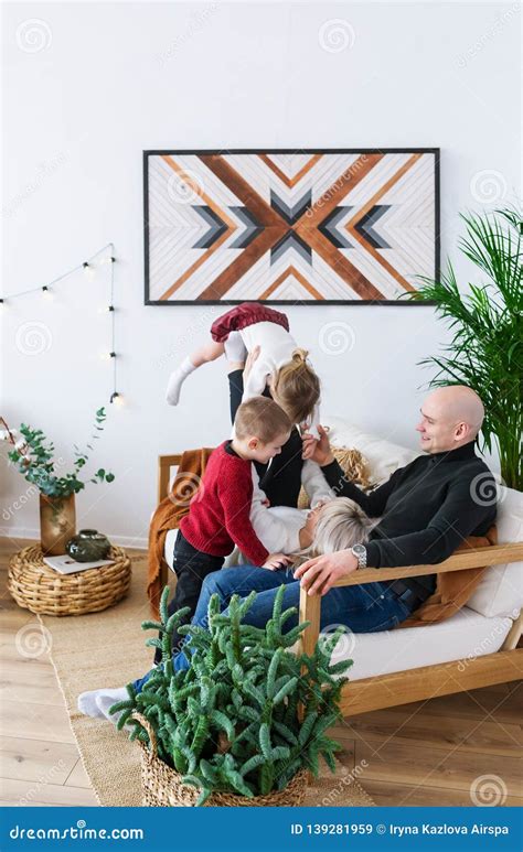 Happy Parents And Kids Having Fun Sitting Together On Sofa In Living