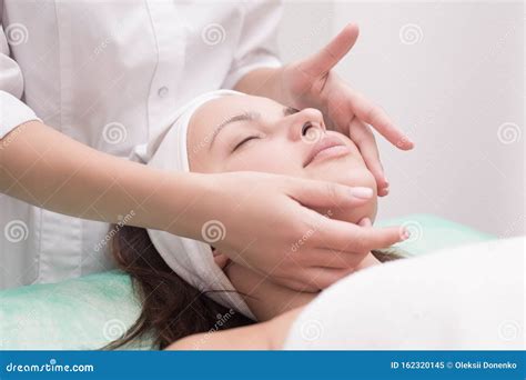Girl Massage Therapist Does Facial Massage With A Beautiful Woman Hands Are Closing Stock Image