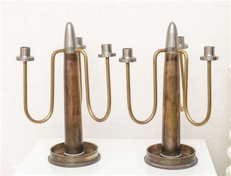 Three Metal Candlesticks Sitting On Top Of A White Table
