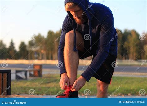 Fit Athlete Handsome Adult Man Runner Tying Shoelaces At Sunset Or