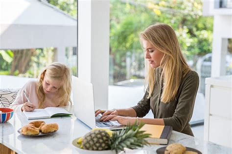 Mom Working On Her Laptop While Daughter Doing Her Homework By Jovo