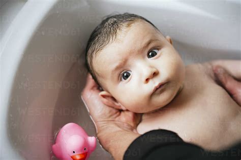 Woman Bathing Baby In A Tub Stock Photo