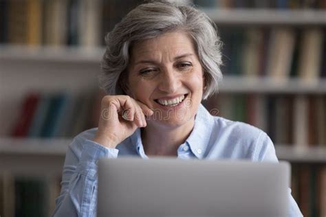 Head Shot Smiling Older Woman Working Remotely On Computer Stock Photo