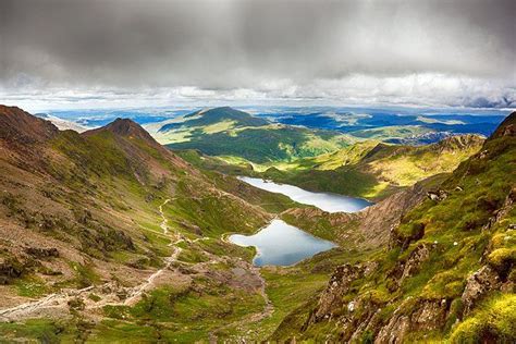 The Mountains Are Covered In Green Grass And Water Under A Cloudy Sky