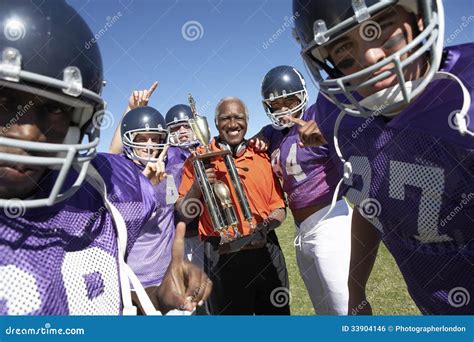 Football Team And Coach With Trophy Celebrating Victory On Field Stock