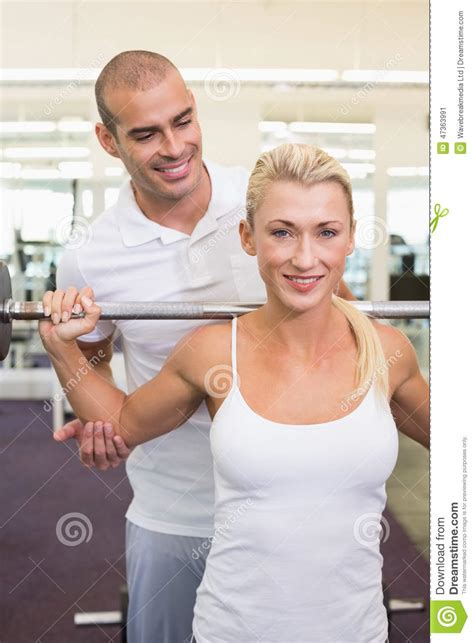 Trainer Helping Woman With Lifting Barbell In Gym Stock Image Image