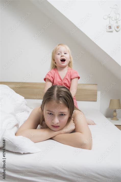 Young Teenage Girl On A Bed On A Saturday Morning Along With Her Younger Sister Attempt To