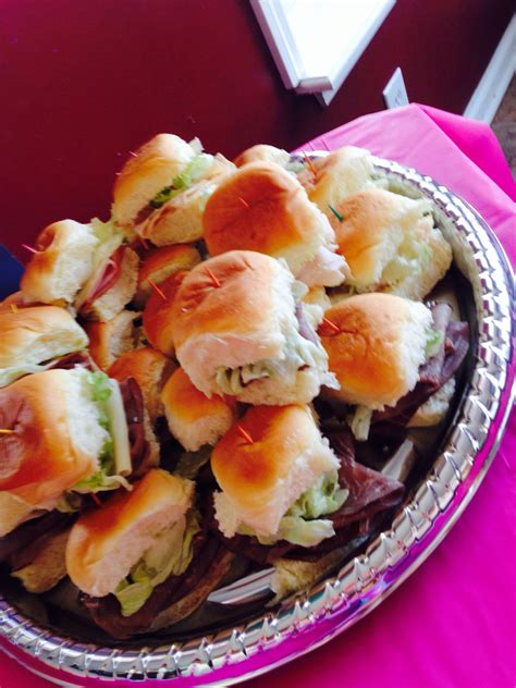 A Platter Filled With Sandwiches On Top Of A Pink Table Cloth