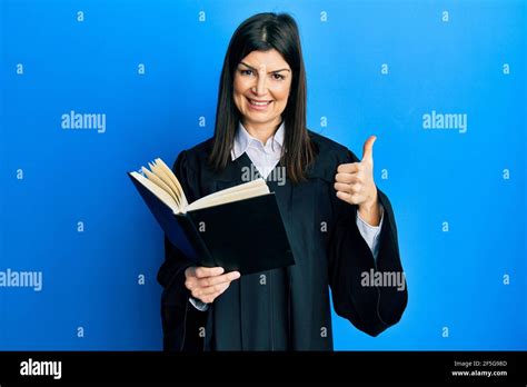 Young Hispanic Woman Wearing Judge Uniform Reading Book Smiling Happy