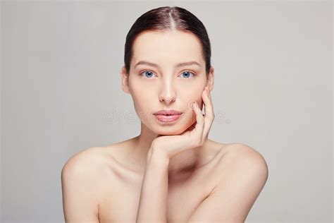 Beautiful Young Woman With Fresh Clean Skin That Touches Her Face With A Right Hand Looking