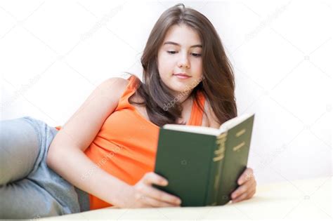 linda chica acostada en la cama en casa y leyendo un libro adolescente acostada en la cama y