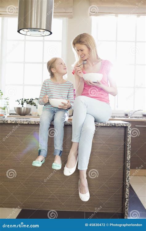 Madre E Hija Que Miran Uno A Mientras Que Desayunando En Cocina Foto De