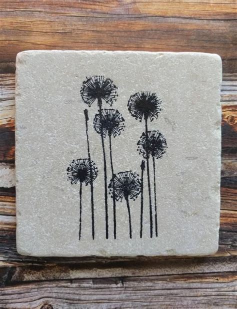 A Stone Coaster With Black Dandelions On It