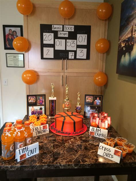 A Table Topped With An Orange Cake Covered In Candies And Balloons Next